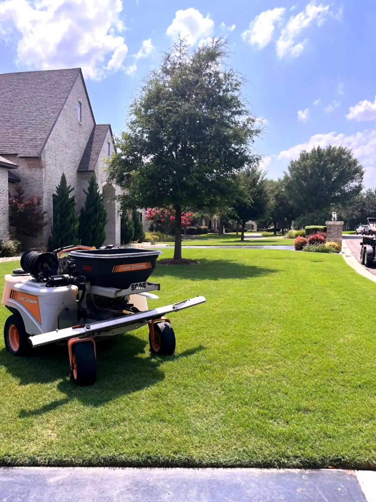 A zero-turn mower on a striped, freshly cut residential lawn.