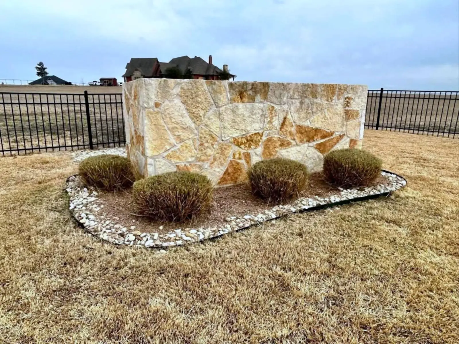Stone entry monument with river rock border and ornamental grasses installed by H&M.